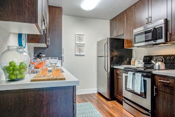 Model home kitchen with dishwasher, stove, refrigerator, quartz countertops and hardwood inspired flooring.at Folsom Ranch, Folsom, CA
